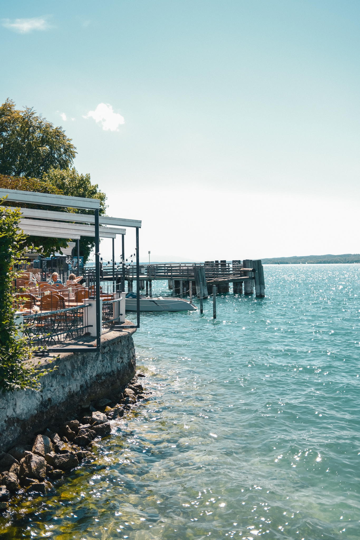 Die Seeterrasse des Strandhotel Berg mit Markisen und Bootssteg am Starnberger See